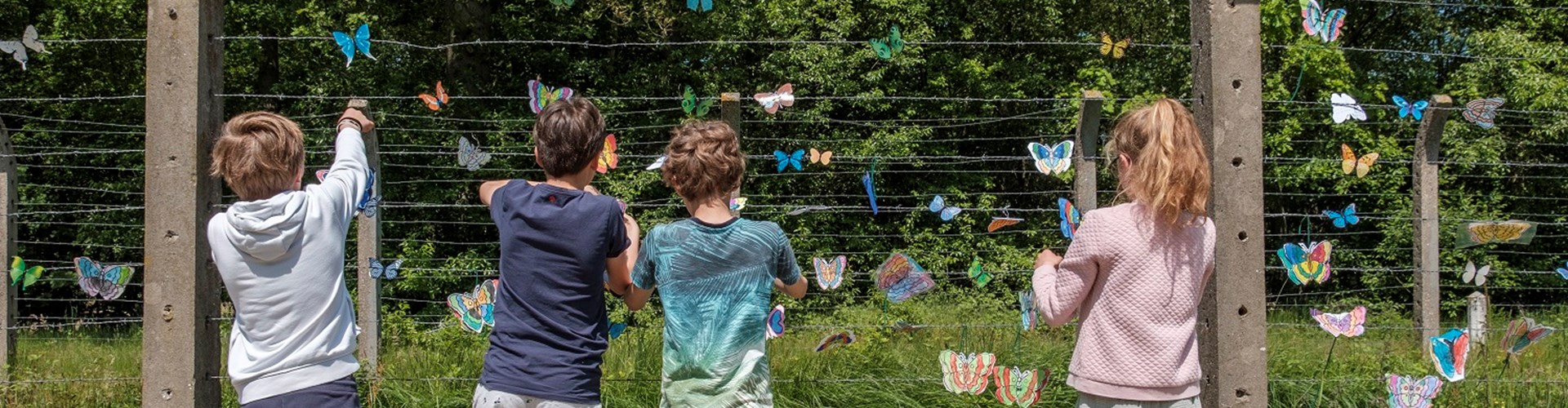 Kinderen hangen vlinders in het hek bij de herdenking van de kindertransporten. Beeld Jan van de Ven
